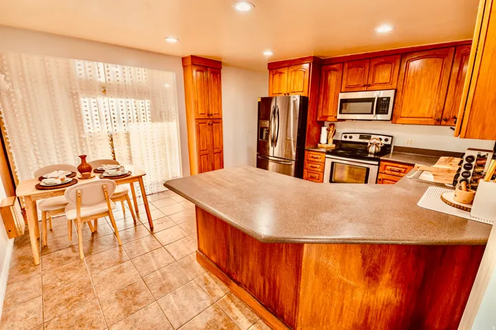 Kitchen featuring wood cabinetry, stainless steel appliances, and a breakfast bar with a solid surface countertop