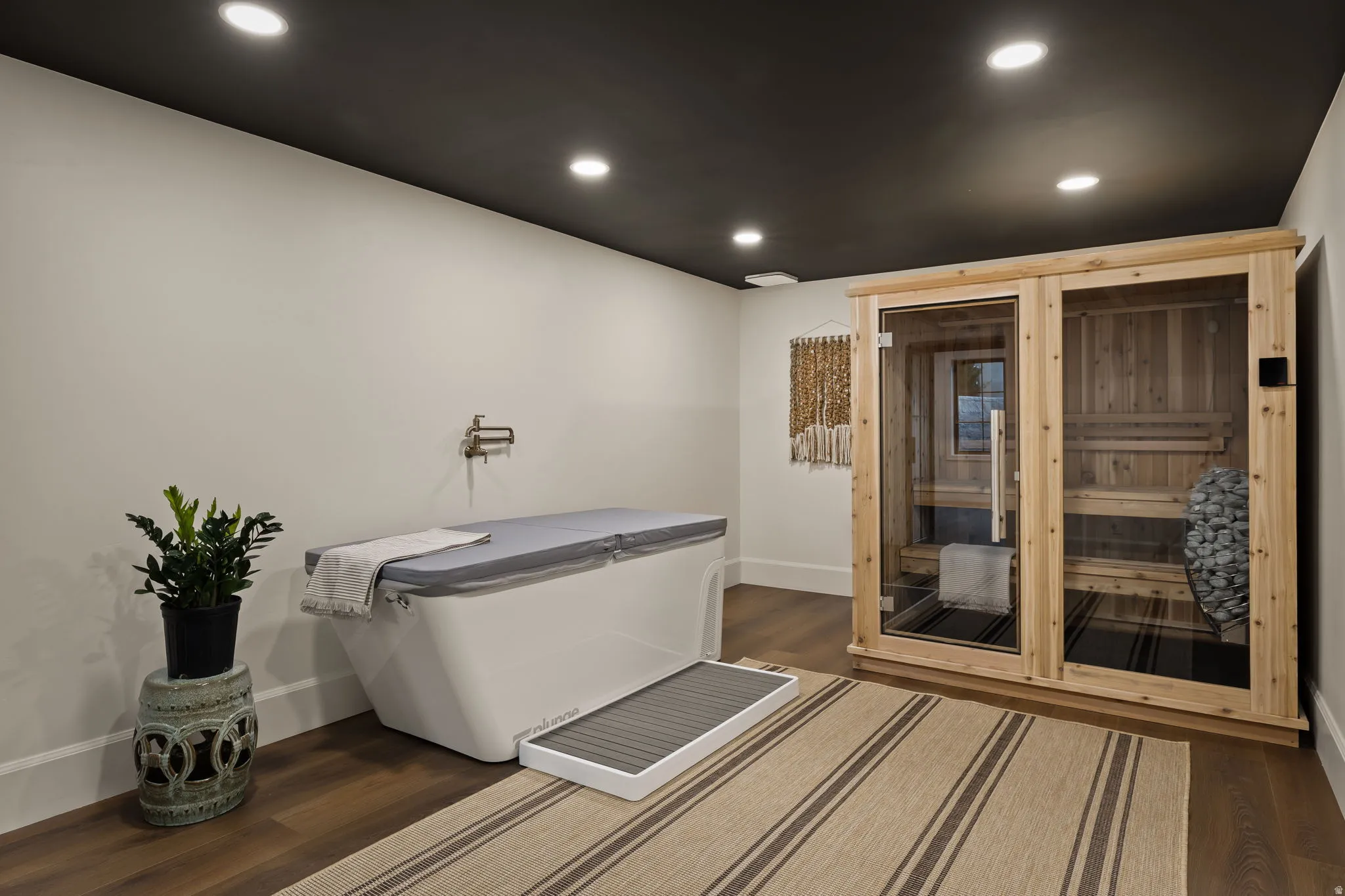 Dedicated wellness space featuring a natural wood sauna with glass doors, recessed ceiling lighting, and wood-finish flooring