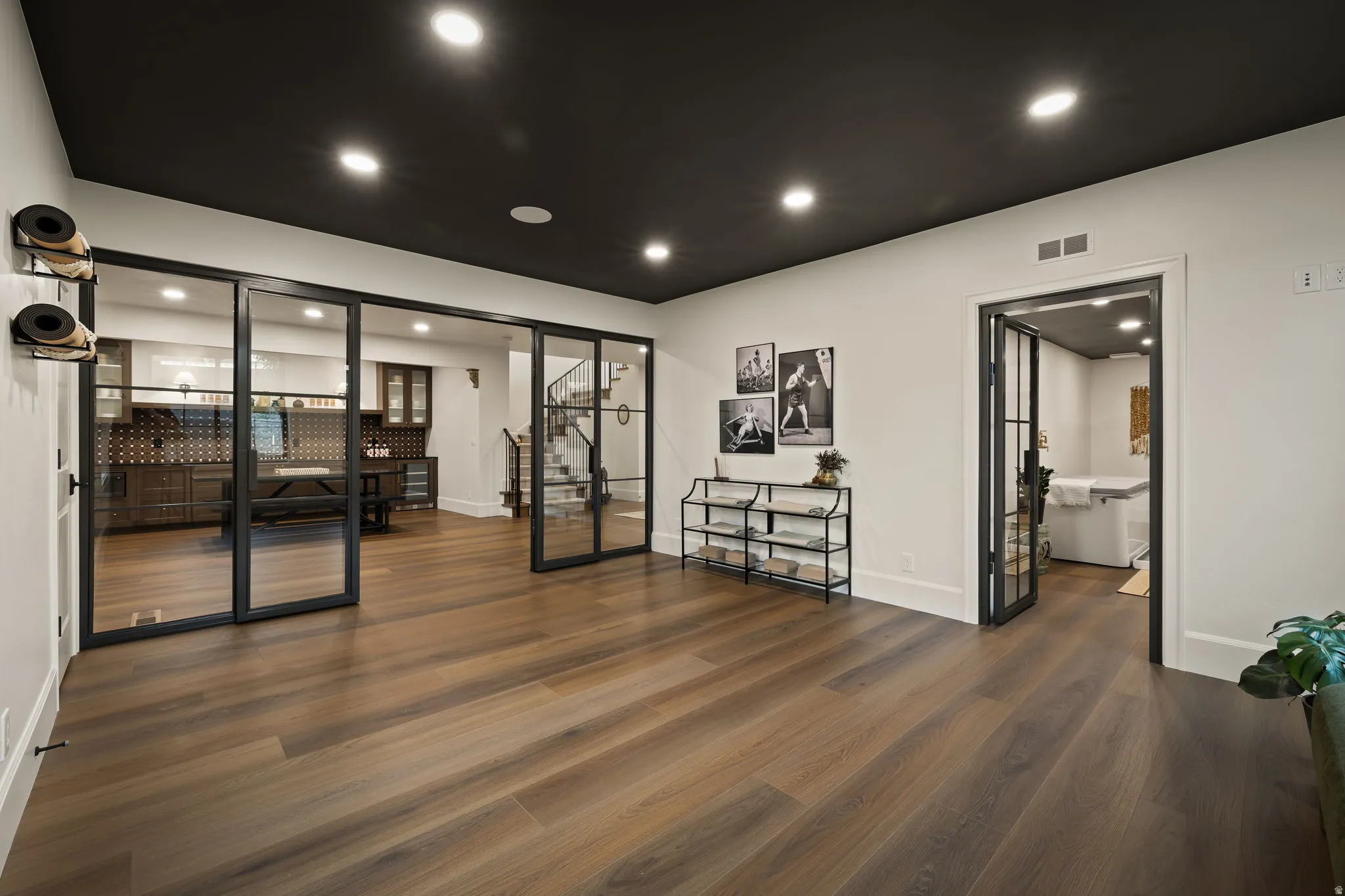 Spacious room featuring wood-finish flooring, a dark ceiling with recessed lighting, and white walls