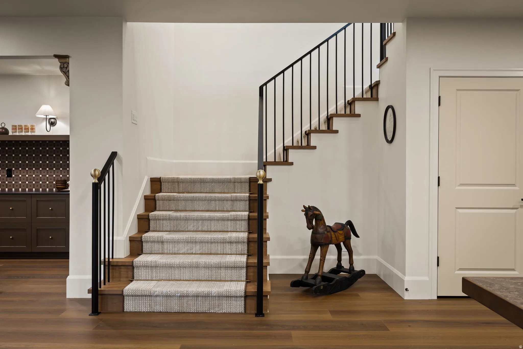 Wood-finish flooring throughout, featuring a carpeted staircase with wood treads and risers