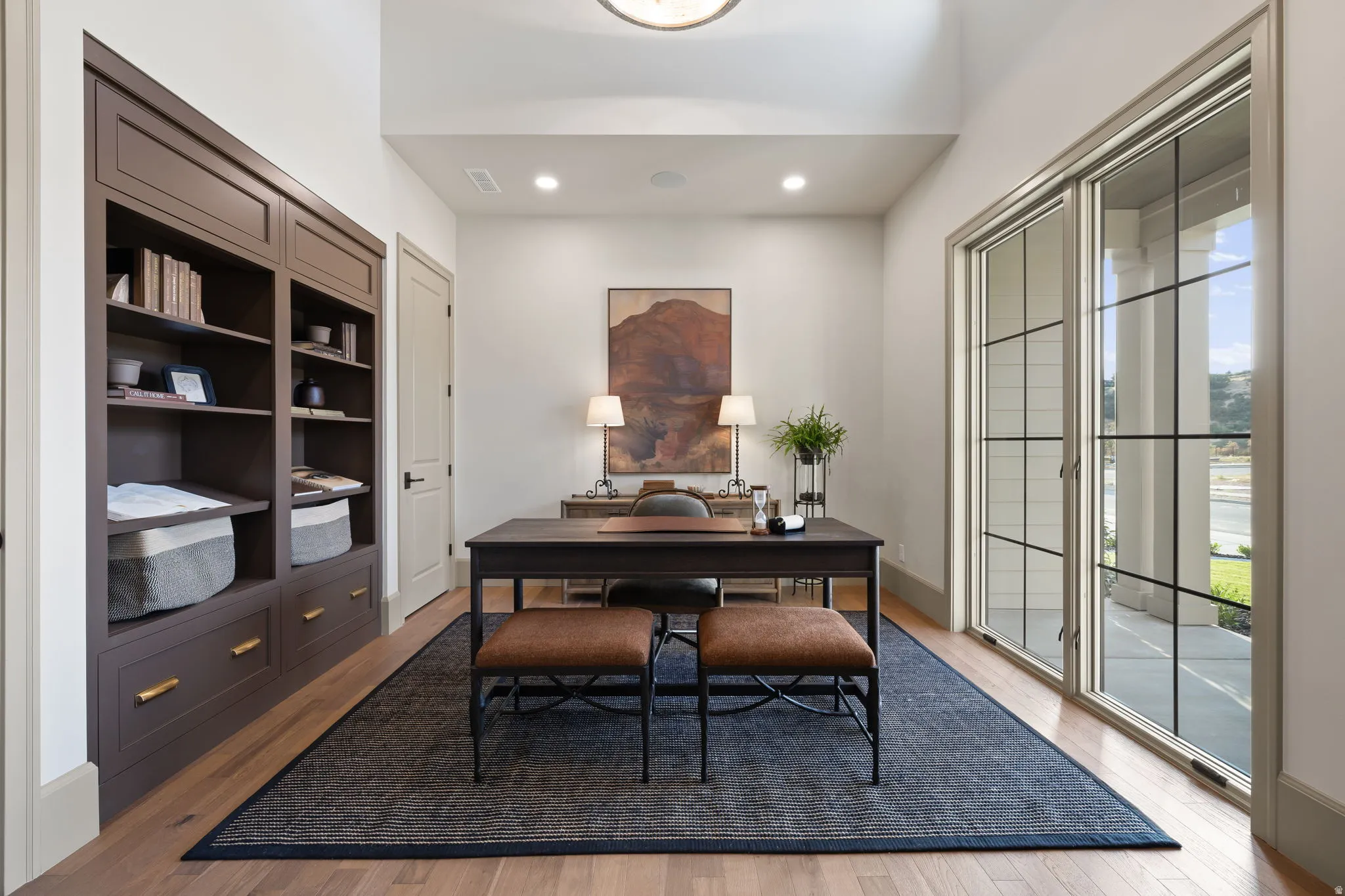 Hardwood-style flooring with a built-in dark wood cabinetry system featuring brass hardware
