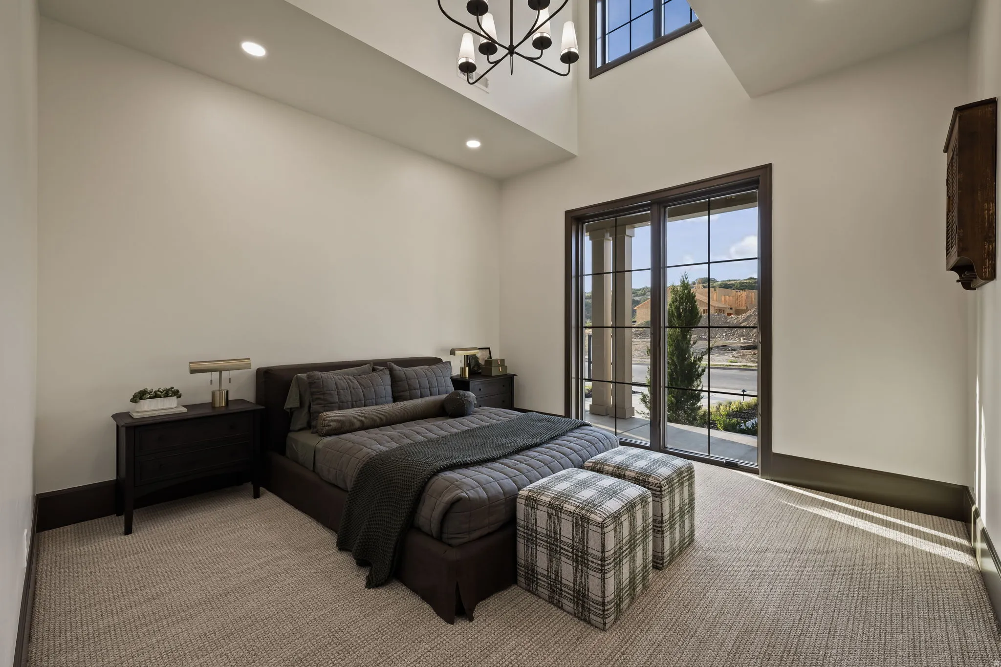 Bedroom featuring a large grid-pattern glass door, high ceilings, recessed lighting, and a modern chandelier