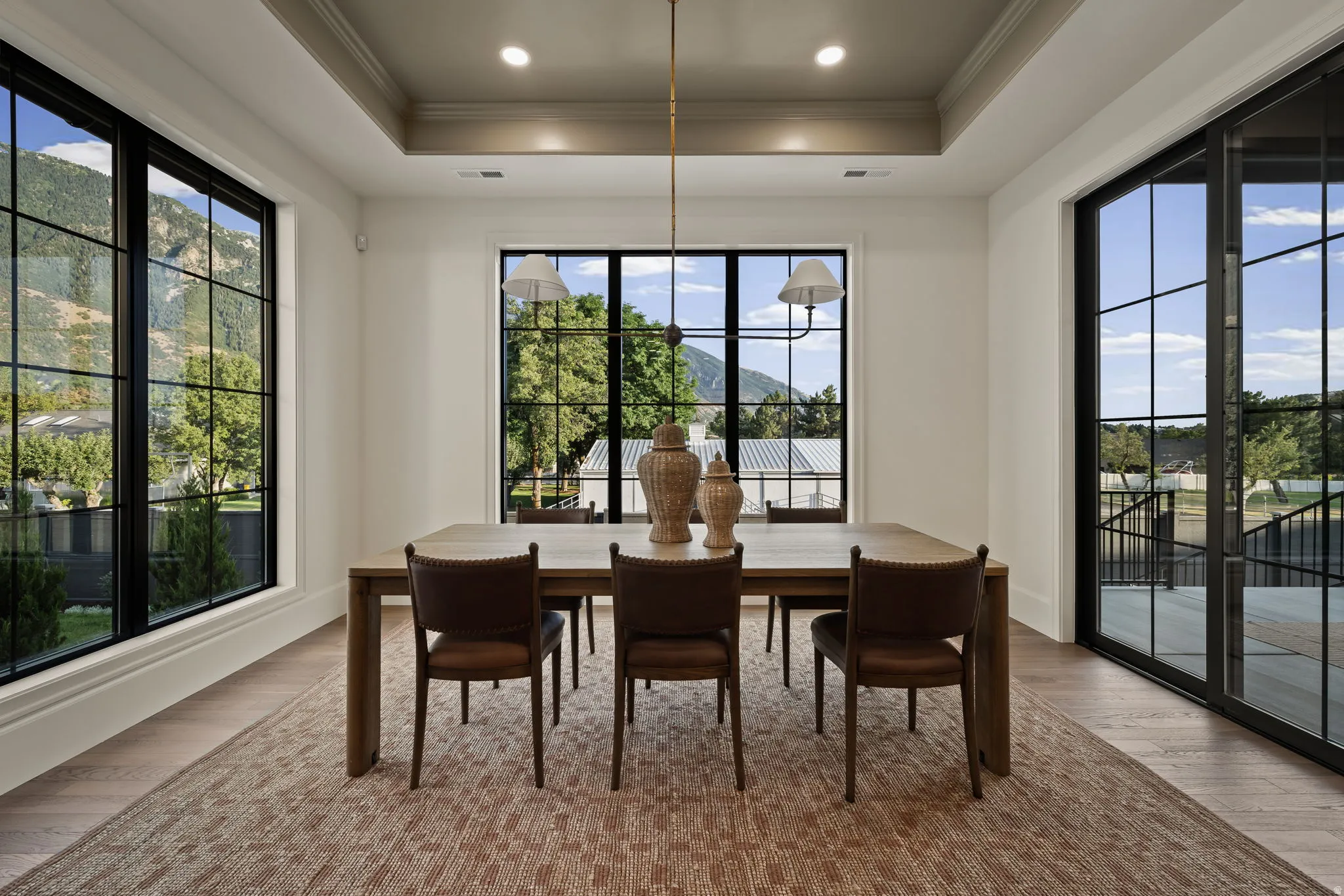 Spacious interior room featuring large grid-pattern windows, a tray ceiling with recessed lighting, and wood-finish flooring