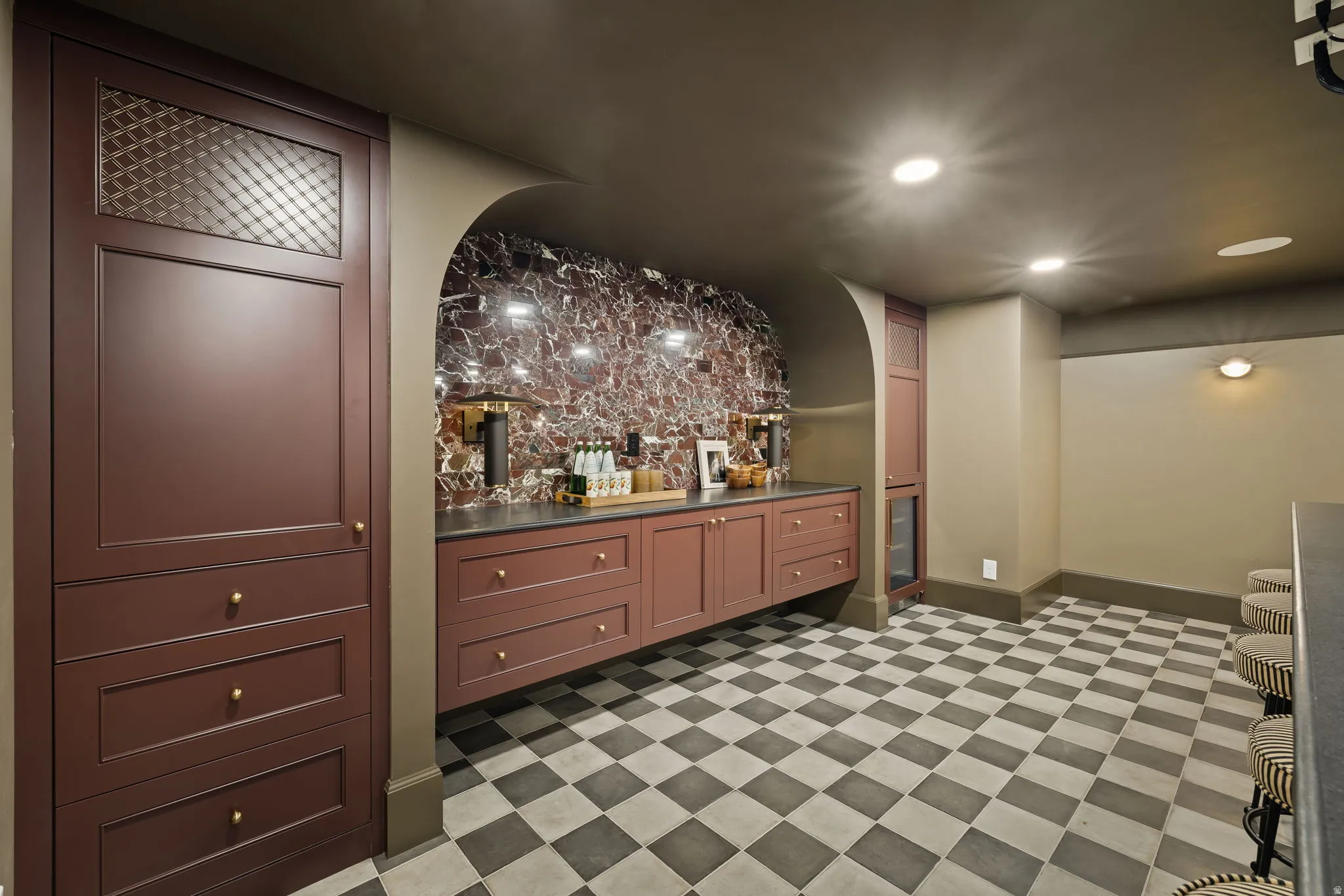 Custom cabinetry with decorative glass panels, a stone-finish countertop, and a built-in beverage refrigerator