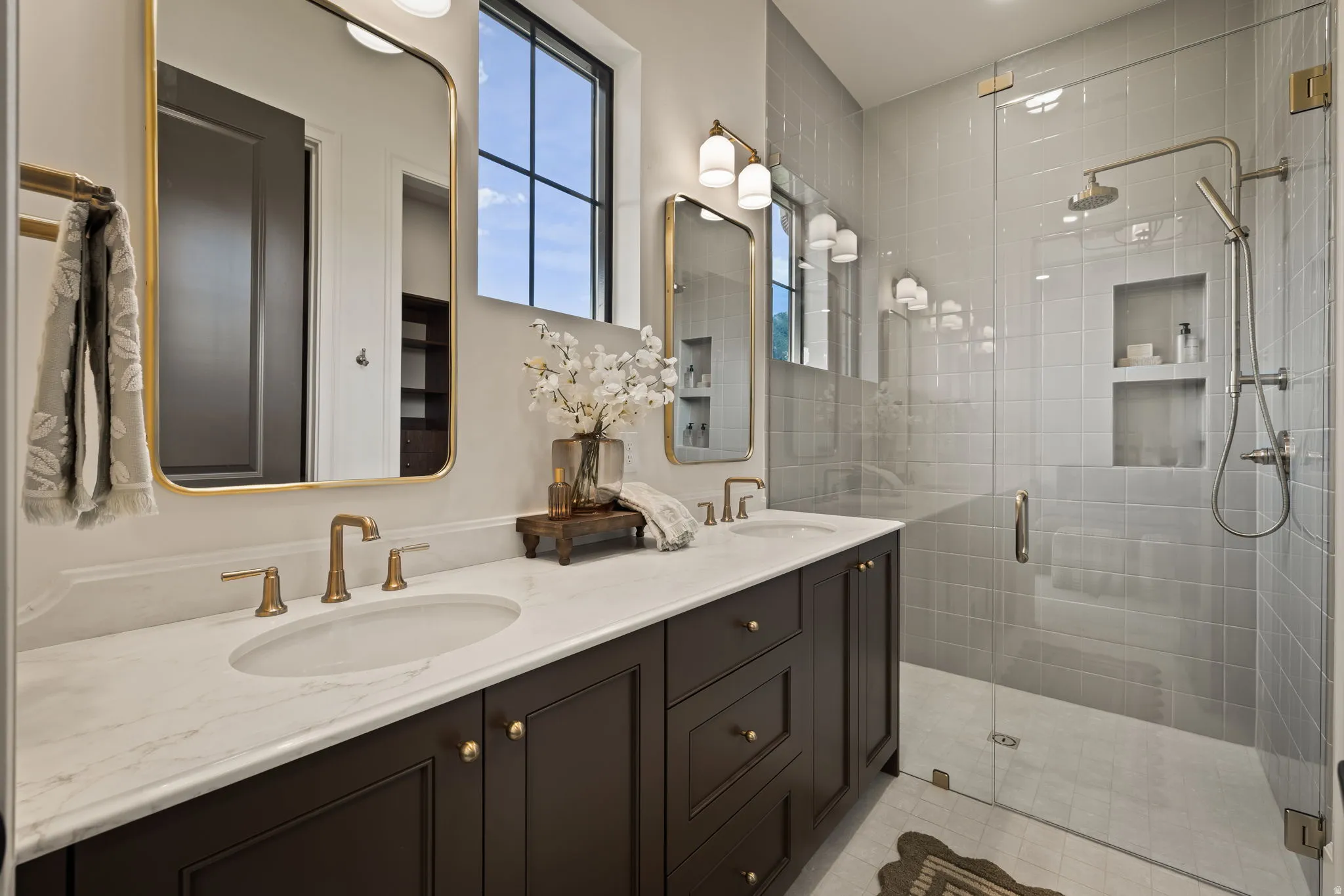 Dual sink vanity with gold-finish hardware, individual framed mirrors, and integrated lighting