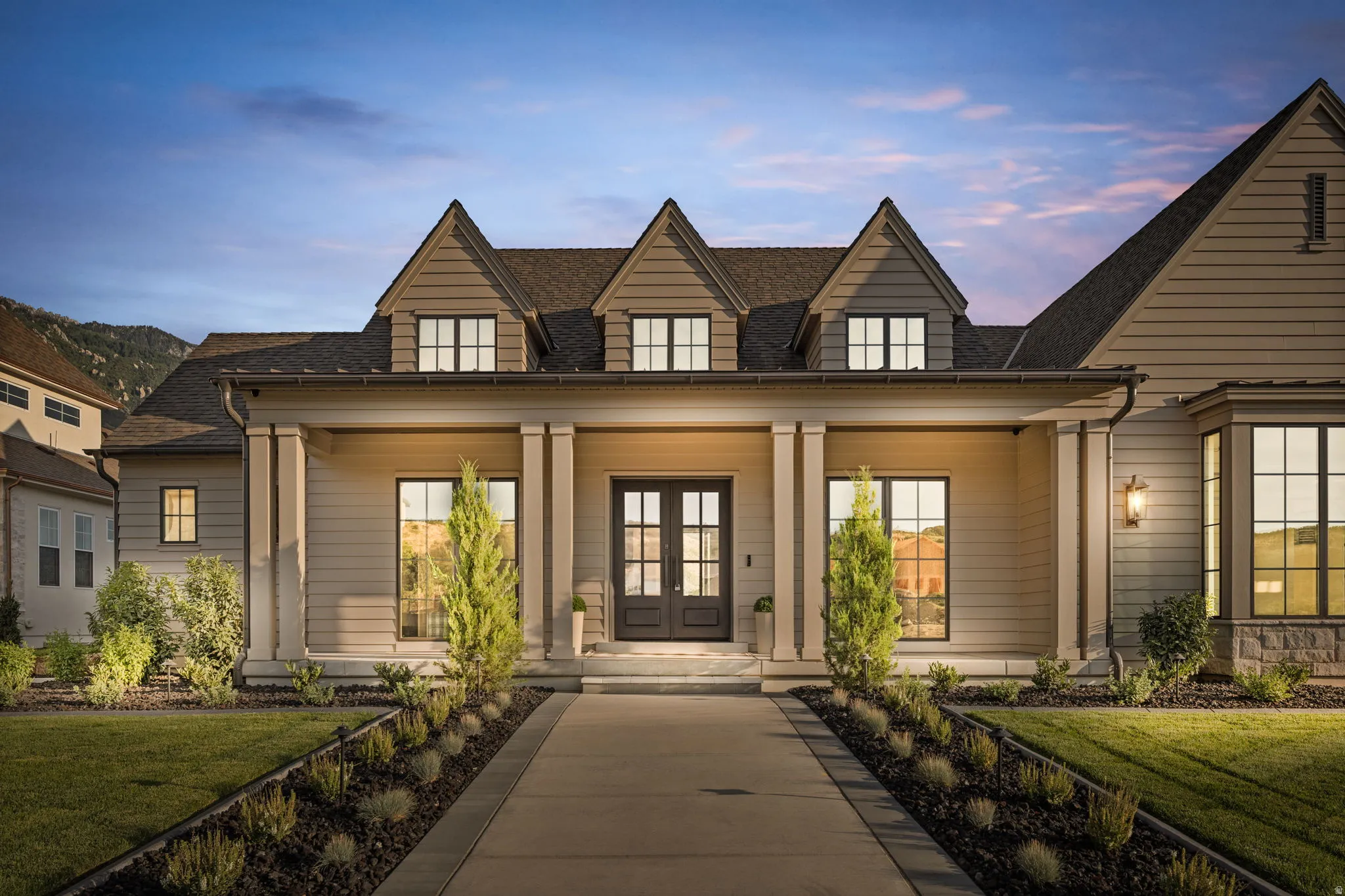 Modern Colonial exterior featuring a covered porch with substantial columns, a gabled roofline, and a stone facade accent