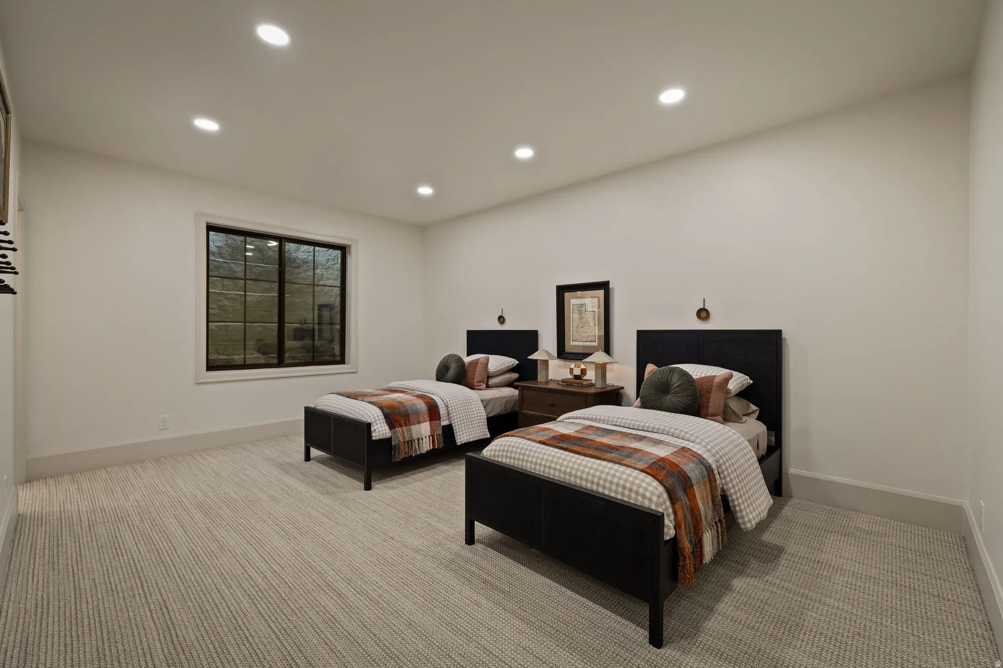 Recessed lighting illuminates a room featuring light-colored walls and striped carpeting
