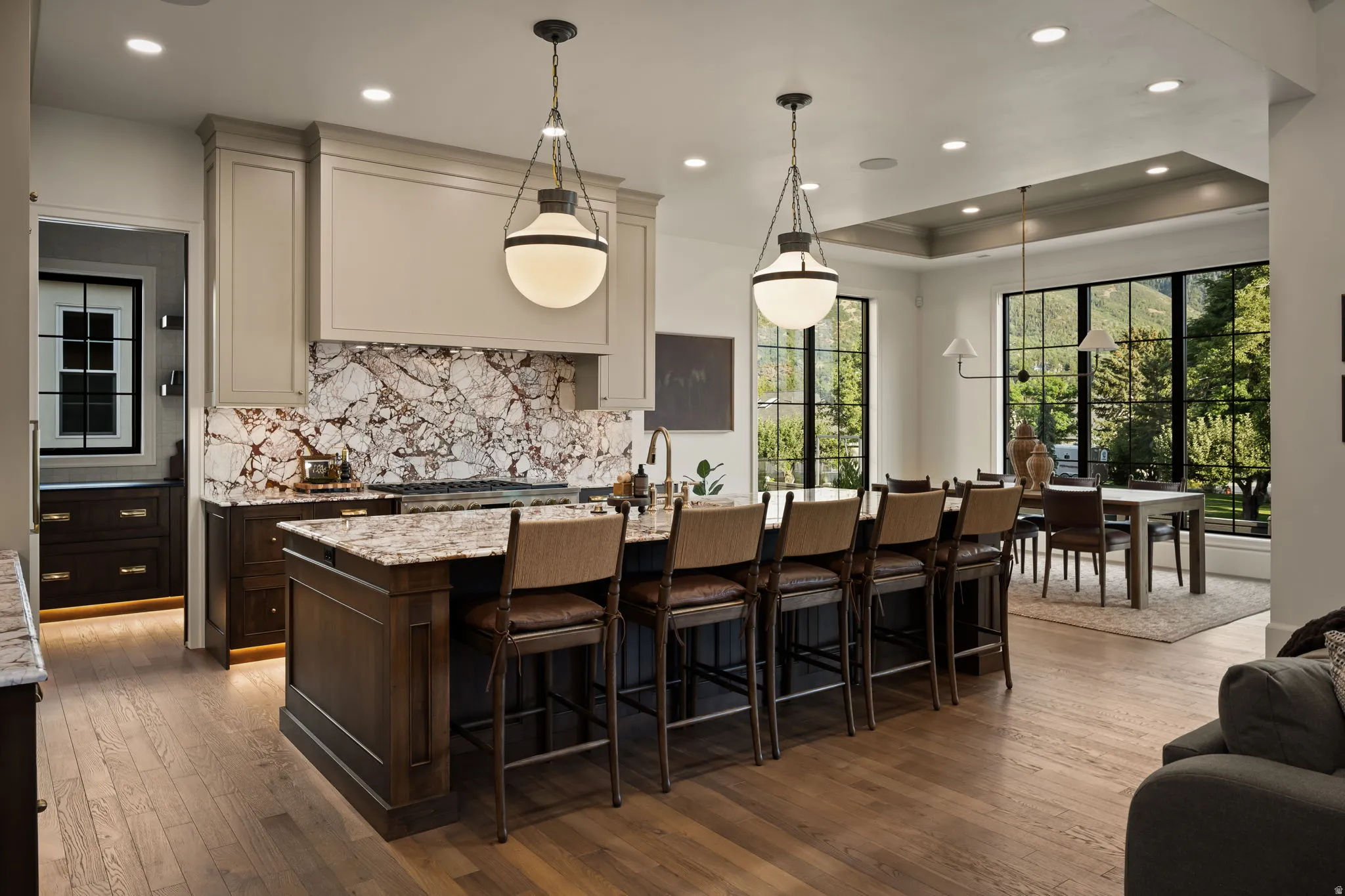 Gourmet kitchen featuring a large island with seating, pendant lighting, professional-grade range, and dramatic slab backsplash