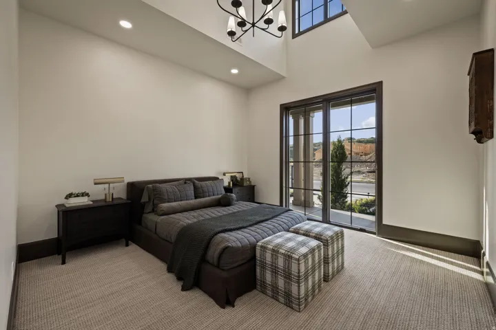 Bedroom featuring a large grid-pattern glass door, high ceilings, recessed lighting, and a modern chandelier