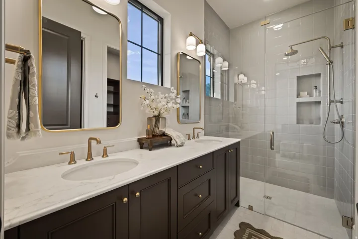 Dual sink vanity with gold-finish hardware, individual framed mirrors, and integrated lighting