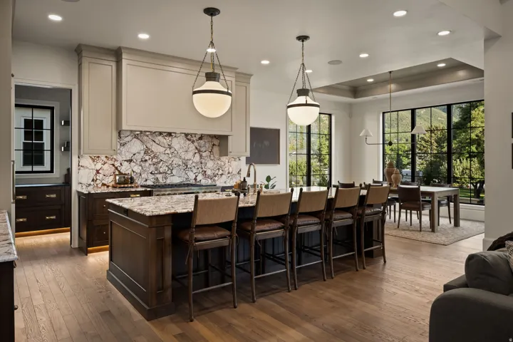 Gourmet kitchen featuring a large island with seating, pendant lighting, professional-grade range, and dramatic slab backsplash