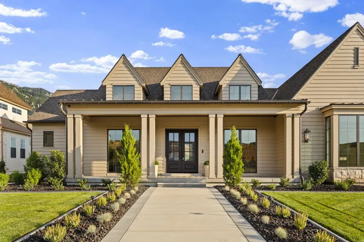 Craftsman-style home featuring a covered entry porch with substantial columns, dormer windows, and a black double-door entry