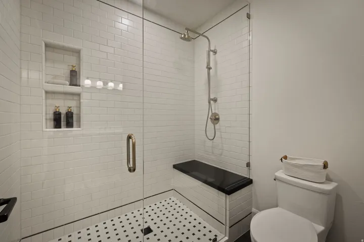 Shower with subway tile walls, integrated shelving, and a black and white mosaic tile floor
