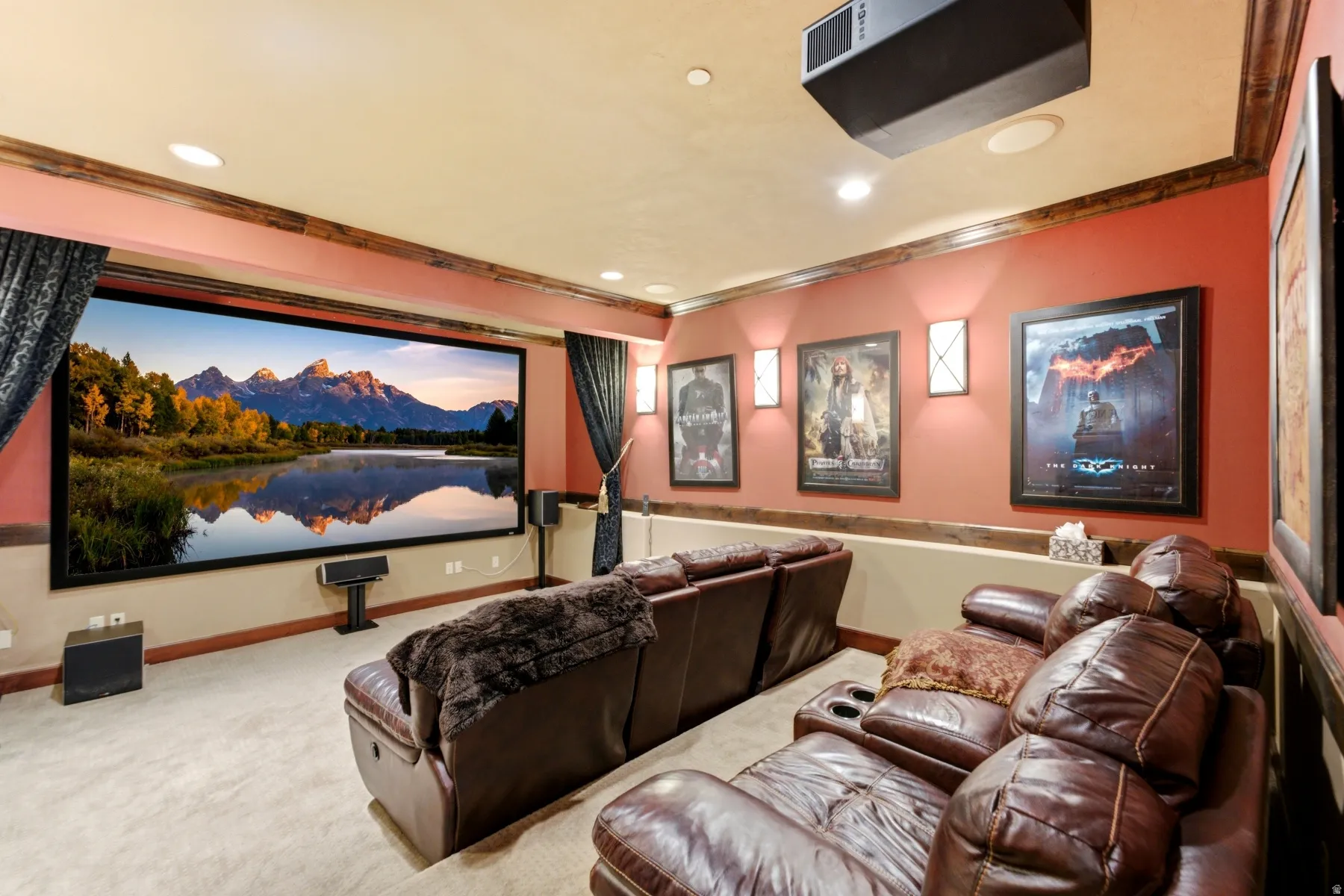 Dedicated media room featuring a large projection screen, wall-mounted speakers, recessed ceiling lighting, and layered wall sconces
