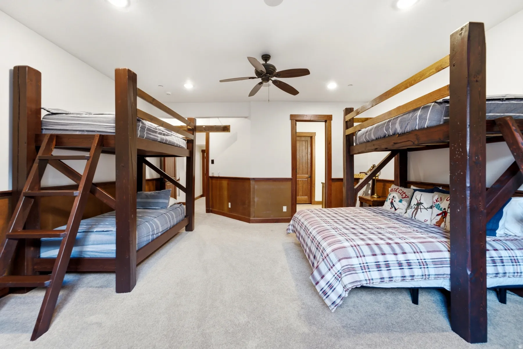 Carpeted room featuring two substantial wooden bunk bed structures, recessed lighting, a ceiling fan, and wainscoting