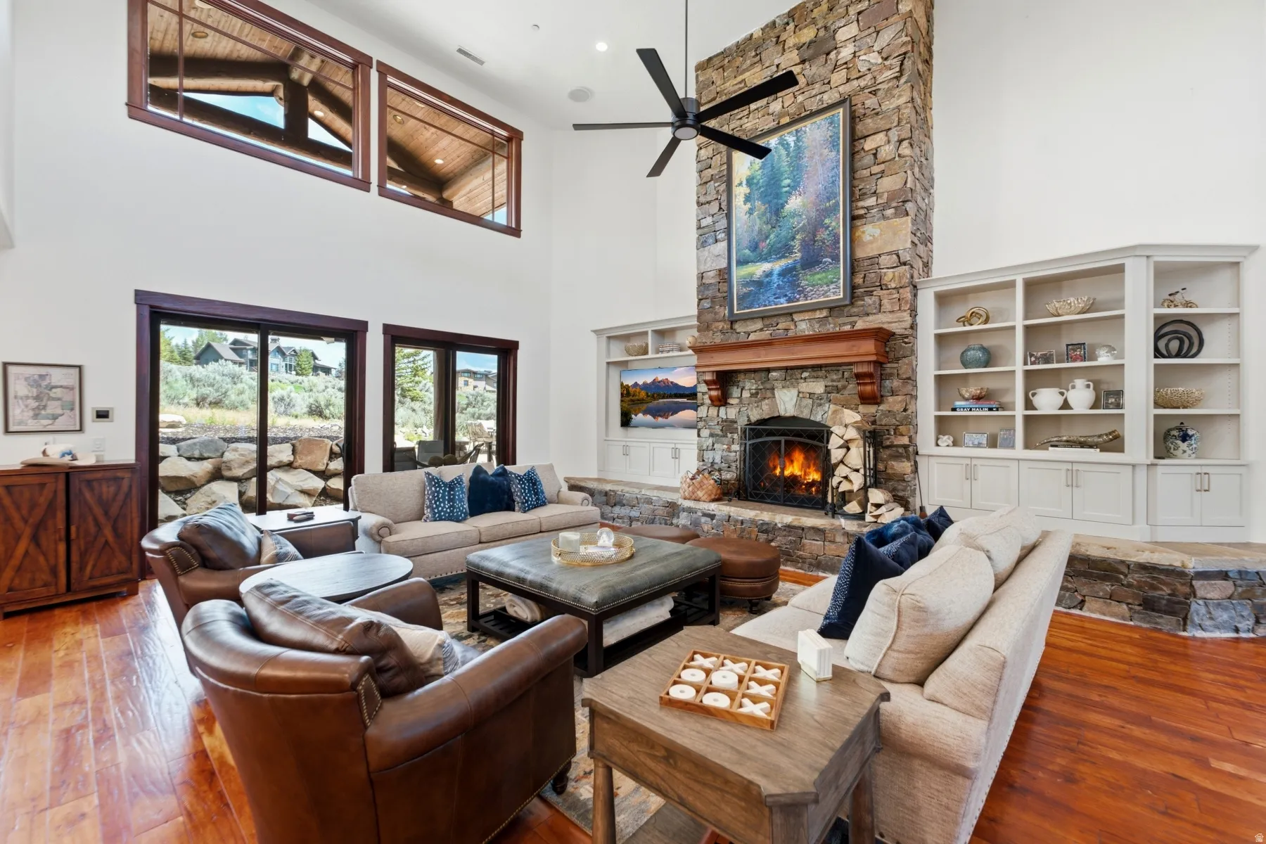 Spacious living area featuring high ceilings, a stone-clad fireplace with a wood mantel, and built-in shelving