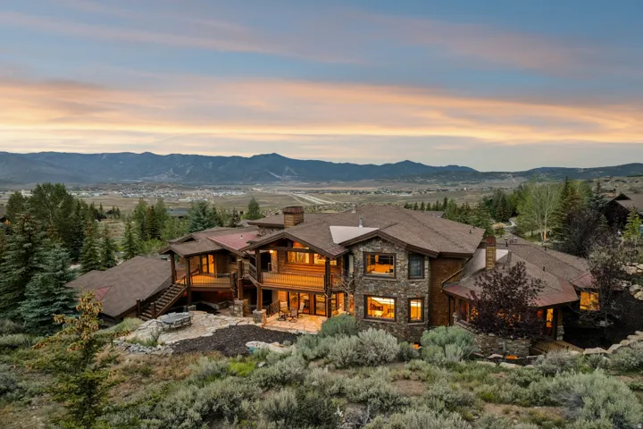 Expansive multi-level residence featuring stone and wood siding, multiple decks, and a prominent stone fireplace chimney