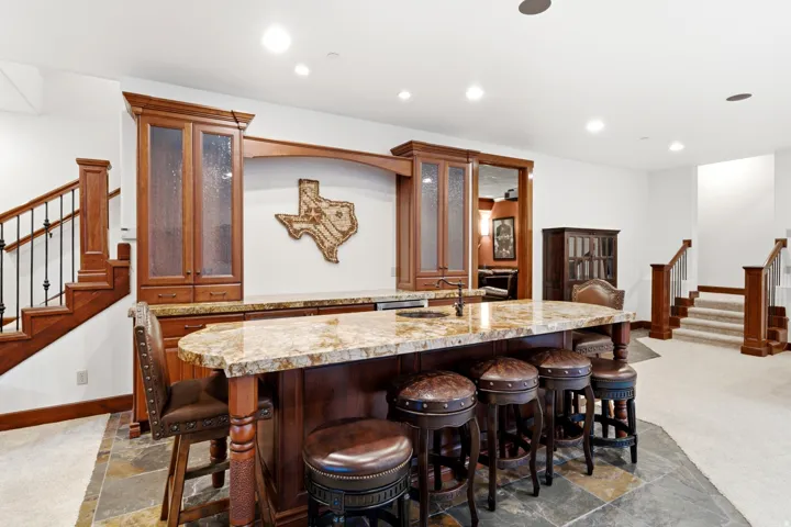 Custom wet bar featuring wood-finish cabinetry, a stone countertop, and a built-in sink