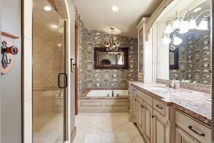 Bathroom featuring a dual vanity with a stone countertop, an undermount sink, and custom cabinetry