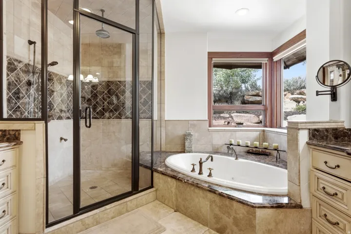 Walk-in shower with glass enclosure and mosaic tile accent, alongside a built-in jetted tub