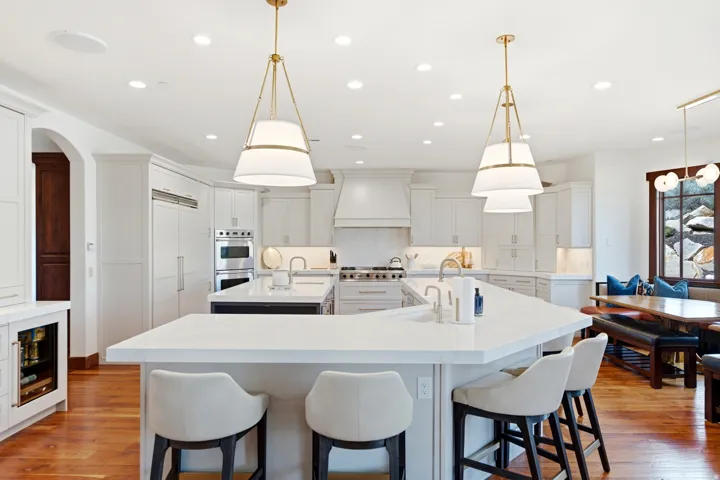 Expansive kitchen featuring a large central island with seating, a secondary island with a prep sink, integrated appliances, and recessed lighting