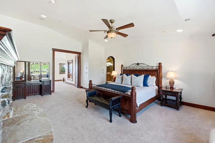 Spacious bedroom featuring vaulted ceilings, recessed lighting, and a stone fireplace with a substantial hearth