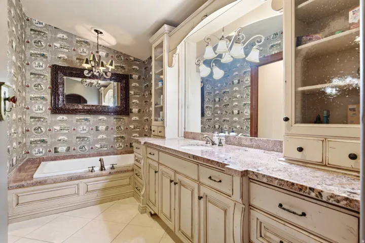 Expansive vanity featuring a granite countertop, dual sinks, and distressed cream-toned cabinetry