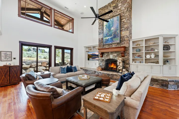 Spacious living area featuring high ceilings, a stone-clad fireplace with a wood mantel, and built-in shelving
