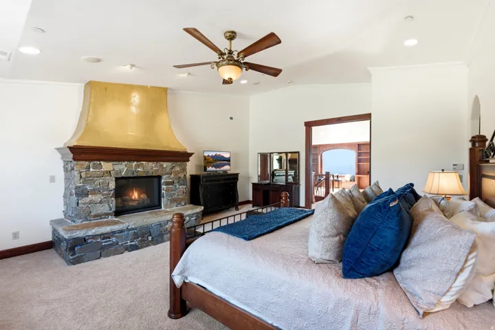Stone-clad fireplace with a decorative hood, wood mantel, and hearth