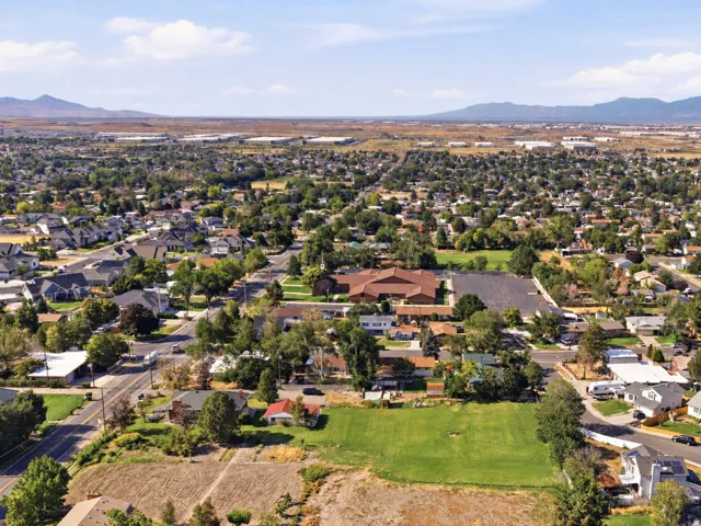 Expansive green space surrounded by established residential areas and mature trees, with distant mountains framing the horizon
