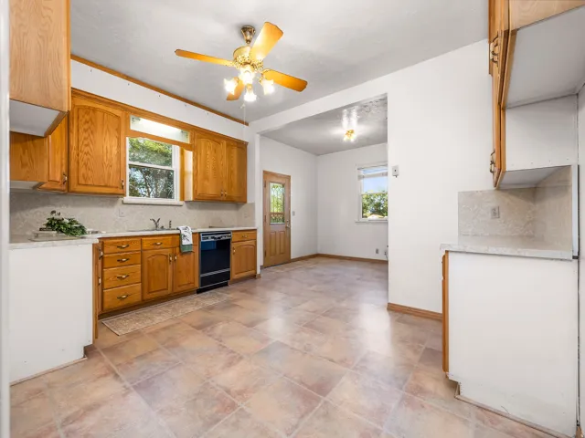 Kitchen featuring wood cabinetry, tiled flooring, an integrated sink, a black range, and a ceiling fan with integrated lighting