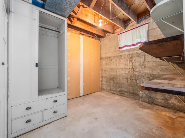 Unfinished basement area featuring exposed ceiling joists and concrete block walls