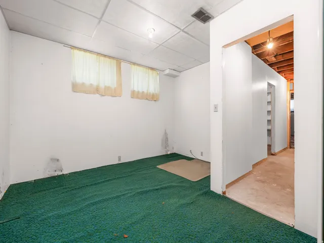 Room featuring two windows with opaque curtains, a drop ceiling, and wall-mounted lighting