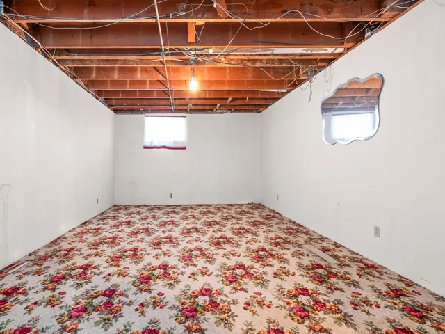 Unfinished ceiling joists and exposed wiring with a single overhead light fixture