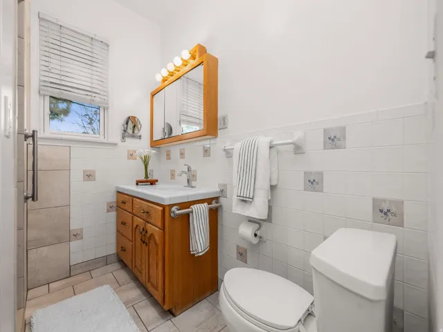 Bathroom featuring a wood vanity with integrated sink, a medicine cabinet with vanity lighting, and a window with blinds