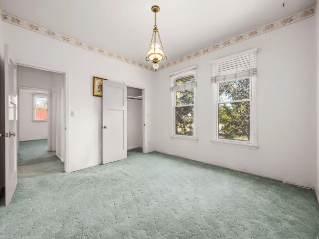 Bright room featuring two windows, recessed closet, light green patterned carpeting, white trim, and a ceiling-mounted light fixture