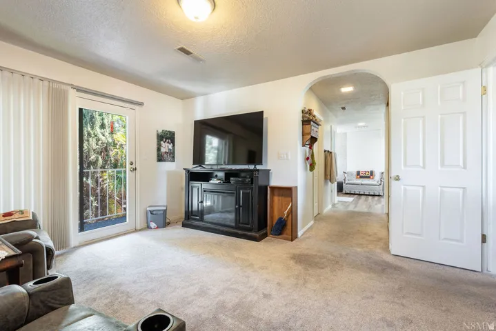 Carpeted living area featuring a glass-paneled door opening to an exterior balcony