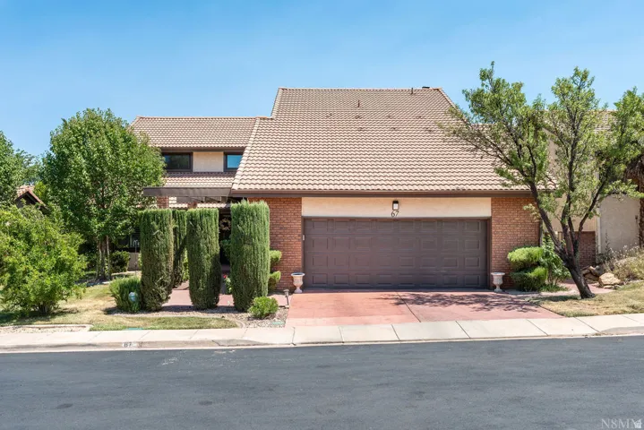 Exterior featuring a two-car garage, brick facade, and a tiled roof