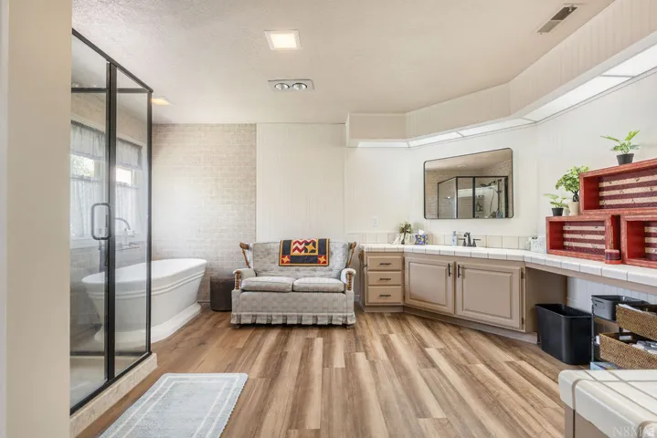 Spacious bathroom featuring wood-finish flooring and a freestanding soaking tub