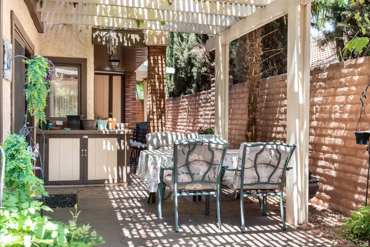 Outdoor patio featuring a white pergola, concrete paver flooring, and a built-in outdoor storage unit