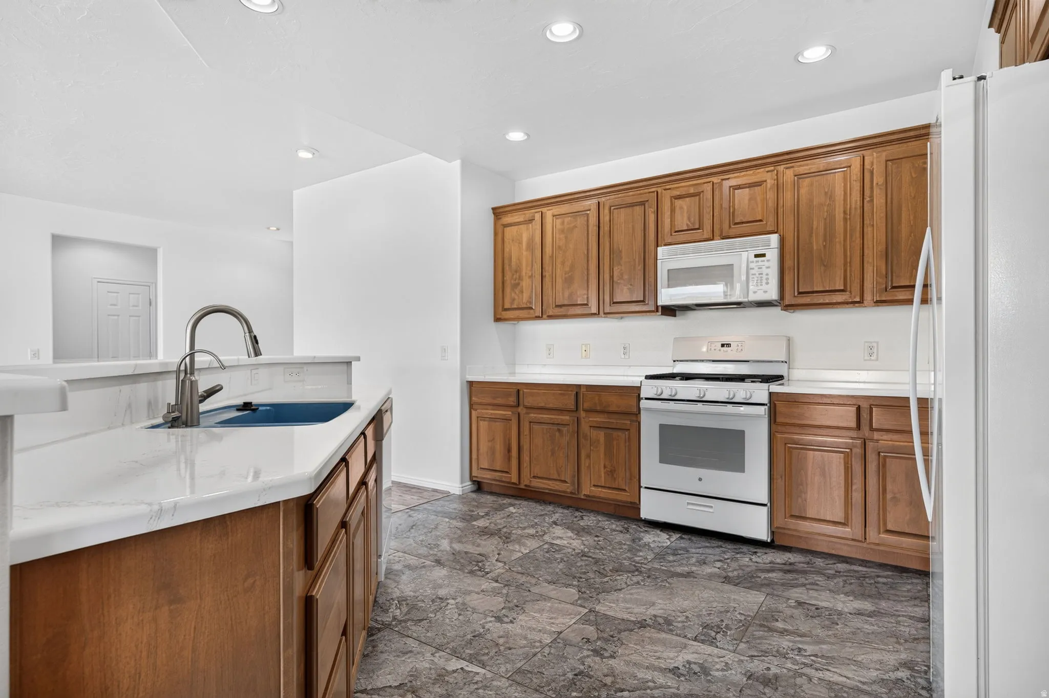 Kitchen featuring warm wood cabinetry, white countertops, stainless steel appliances, and recessed lighting