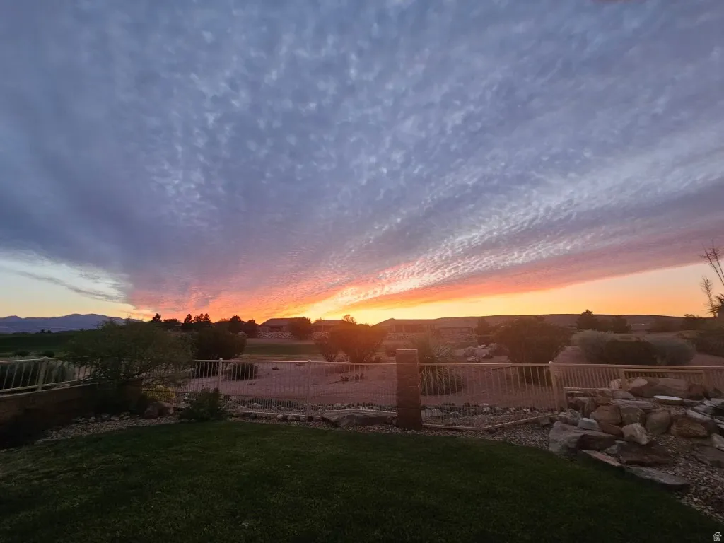 Expansive backyard featuring a manicured lawn, decorative rock landscaping, and a low-profile fence