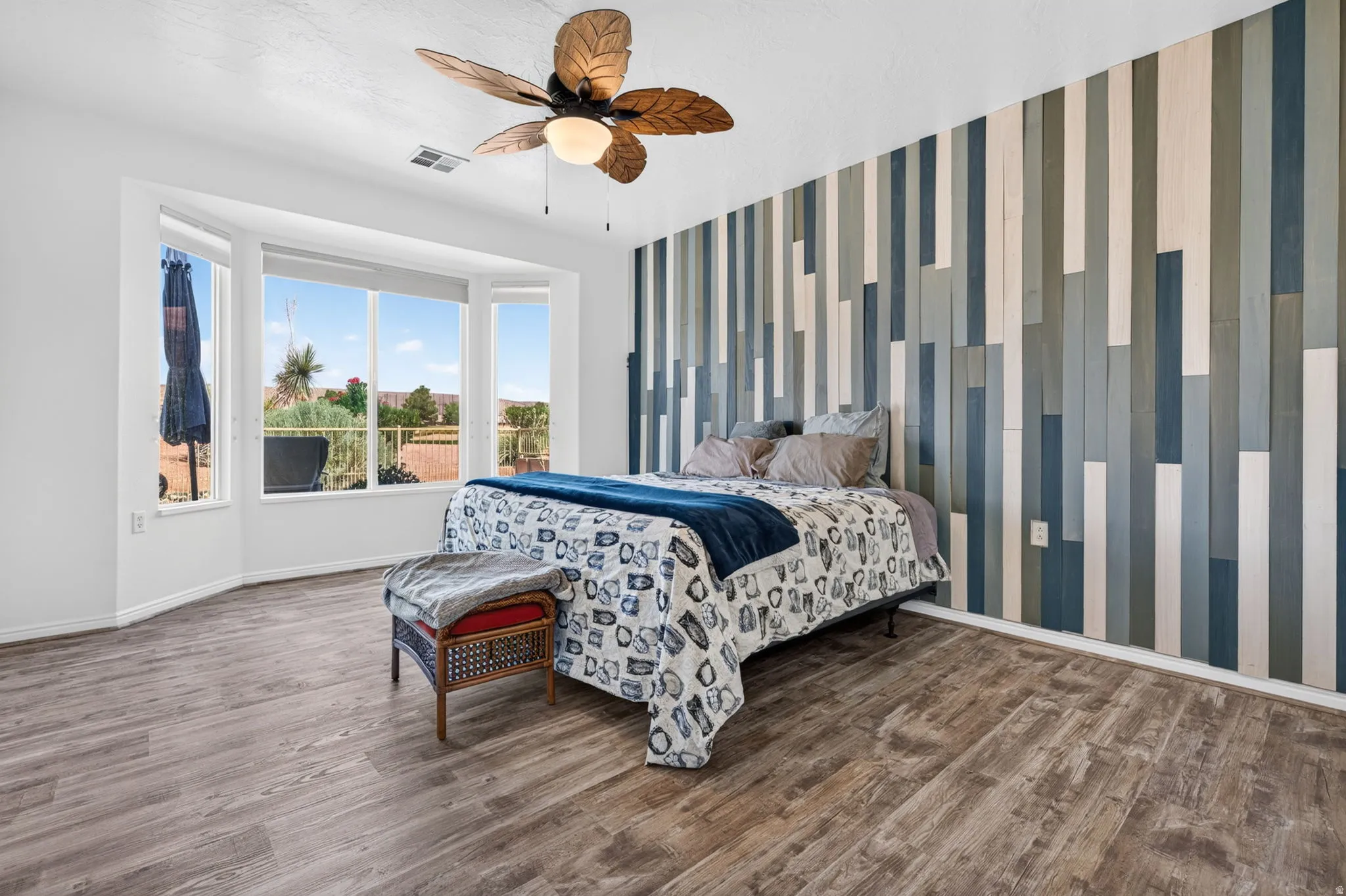 Bedroom featuring a decorative accent wall with vertical wood paneling in varying tones of blue, gray, and white