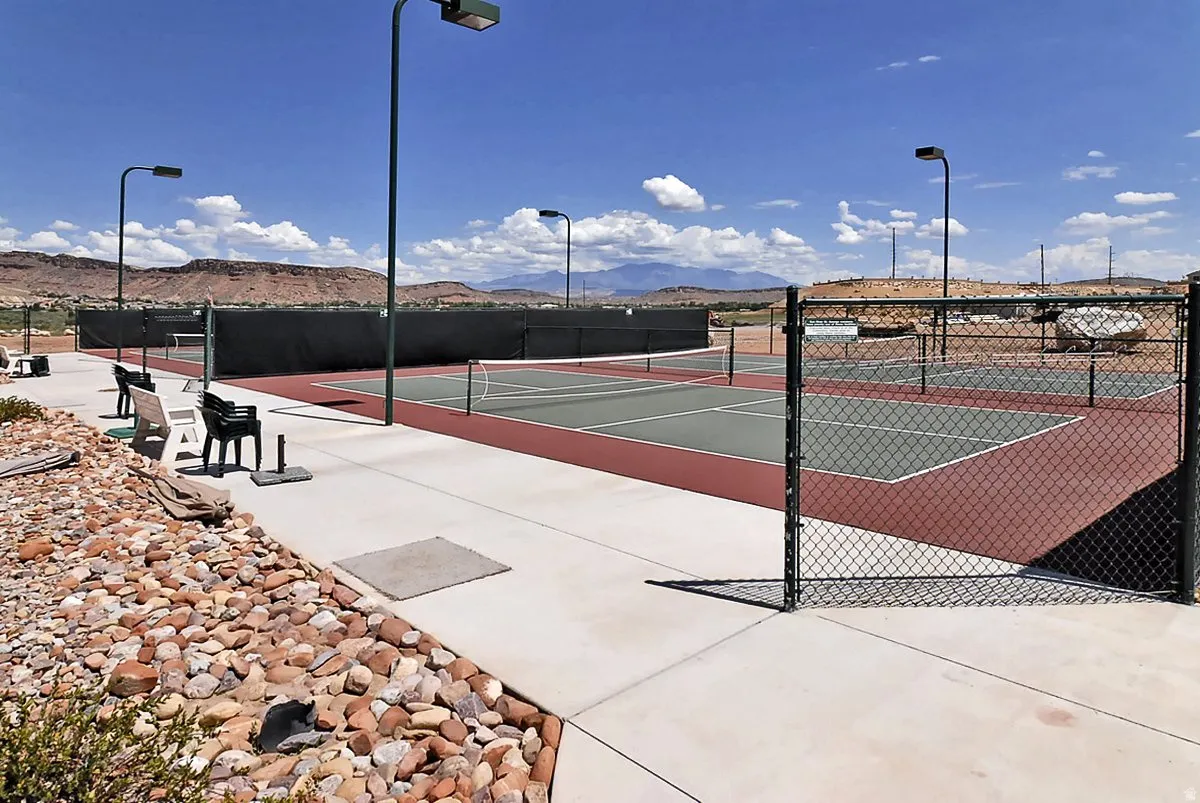 Newly constructed tennis courts featuring professional-grade hard courts with regulation netting, LED lighting for extended play, concrete perimeter decking, and decorative rock landscaping