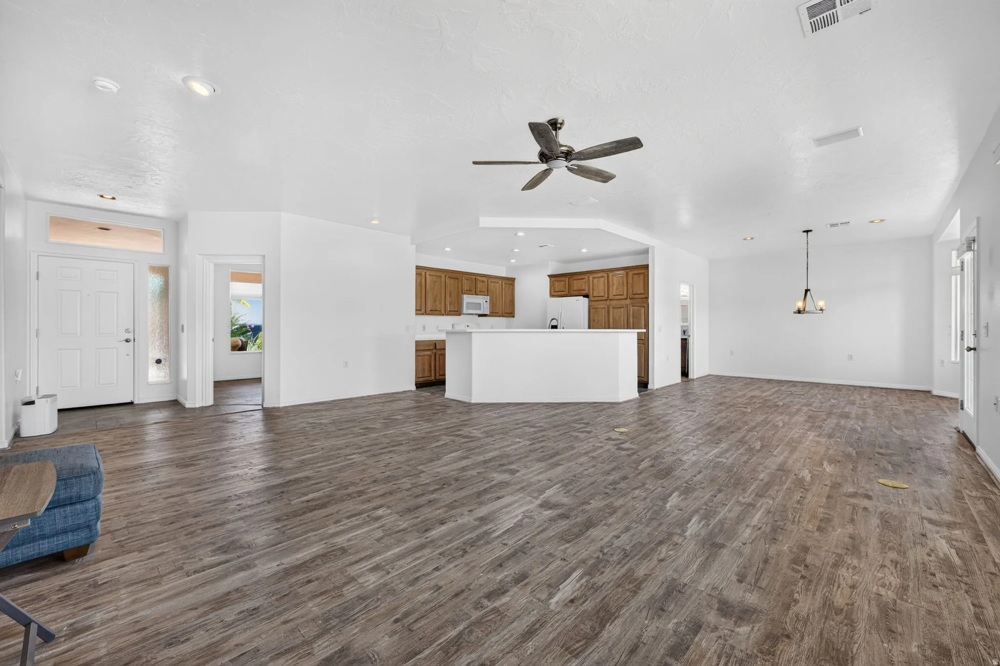 Spacious living area featuring wood-finish flooring, a ceiling fan, and recessed lighting