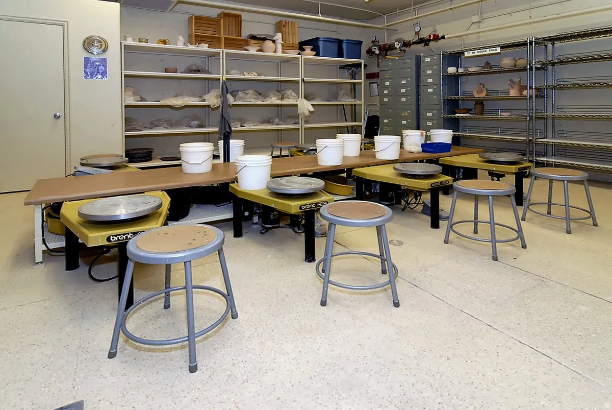 Dedicated instructional or laboratory space featuring multiple workstations with integrated seating, extensive shelving systems throughout, and ample counter surface area for hands-on activities