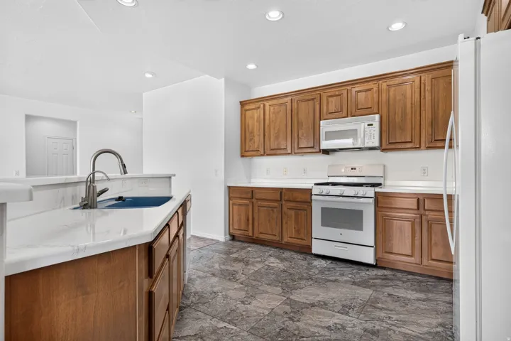 Kitchen featuring warm wood cabinetry, white countertops, stainless steel appliances, and recessed lighting