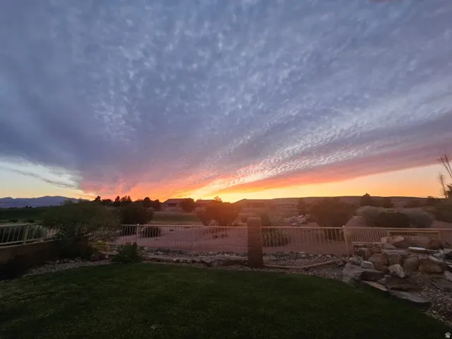 Expansive backyard featuring a manicured lawn, decorative rock landscaping, and a low-profile fence