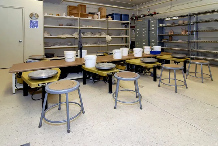 Dedicated instructional or laboratory space featuring multiple workstations with integrated seating, extensive shelving systems throughout, and ample counter surface area for hands-on activities