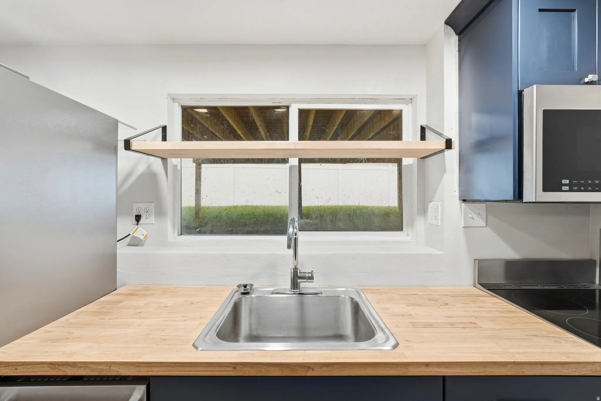 Kitchen space featuring wood-finish countertops, a stainless steel sink with a gooseneck faucet, and blue cabinetry